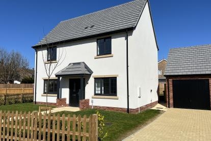 Two storey white house with a paved driveway and garden with a fence in front