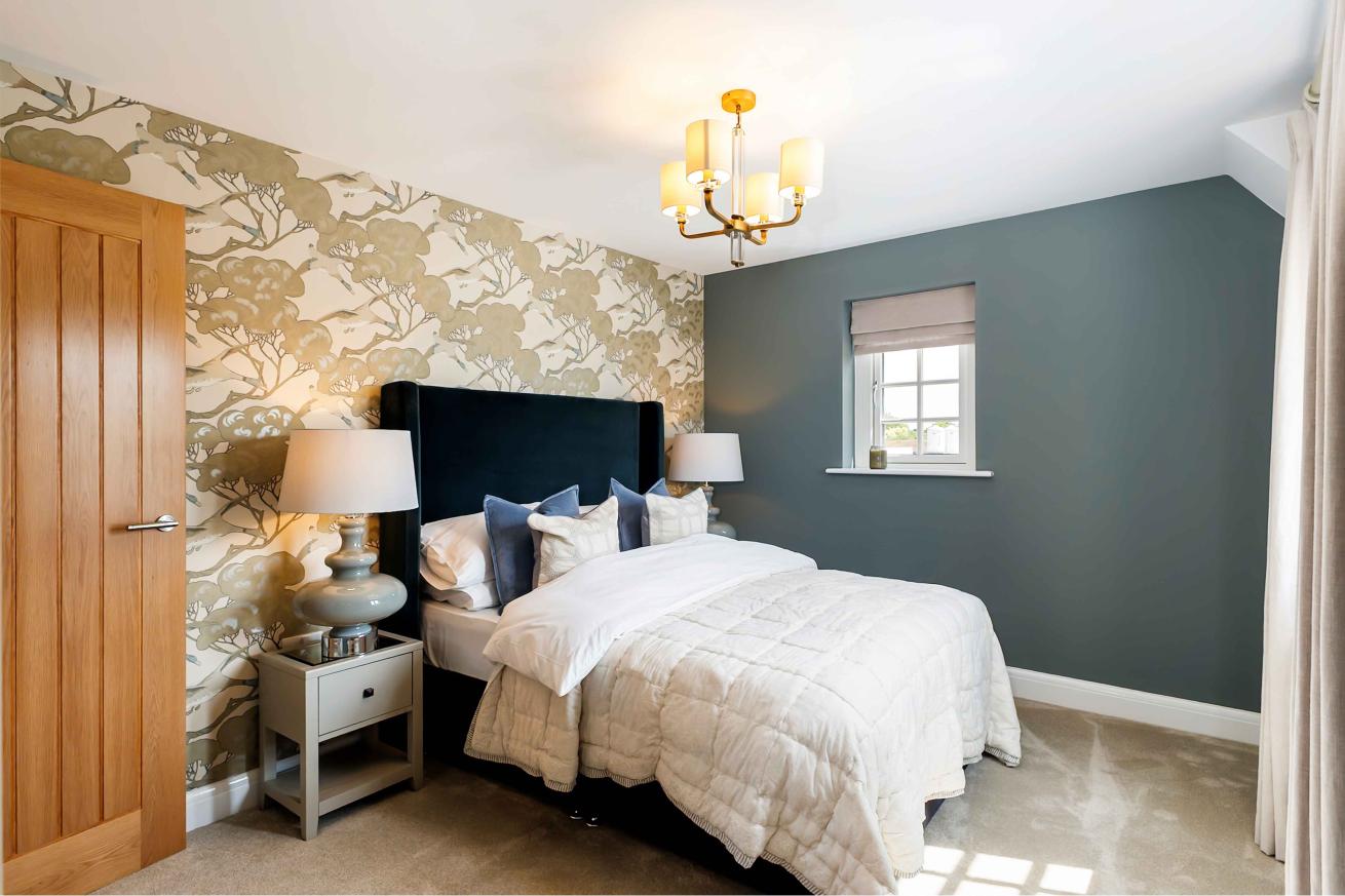 Cozy double bedroom with patterned wallpaper and two side tables. 
