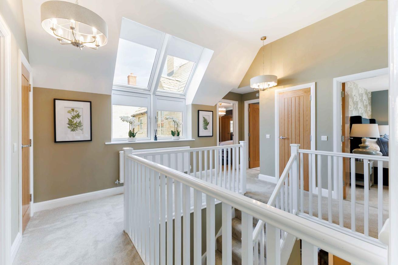 Bright landing area with white bannisters and a window. 