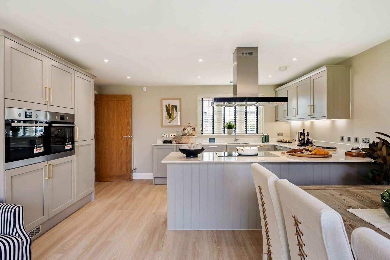 Lightly coloured kitchen units with a white worktop. 