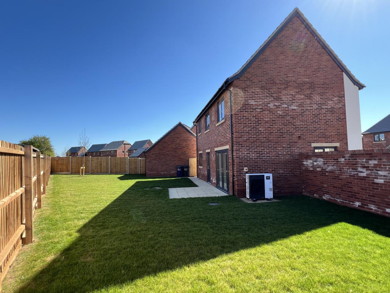 Rear exterior of a redbrick two storey house which backs onto a large fenced in garden